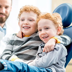 Two young boys smiling in dental chair