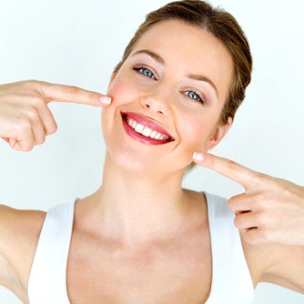 Woman pointing to her healthy smile.