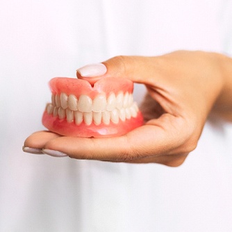 Closeup of Dentist in Farmington holding dentures