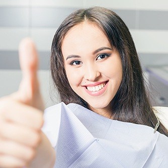 Woman in dental chair giving thumbs up