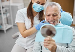 Man smiling at reflection in handheld mirror