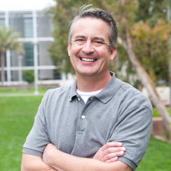 man smiling outside with arms crossed