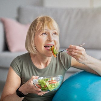 woman eating salad on exercise ball 