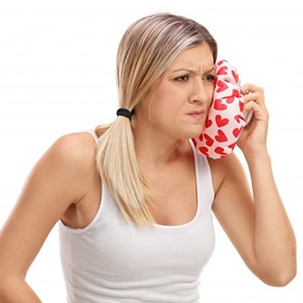 woman in white tank top holding cold compress to her face 