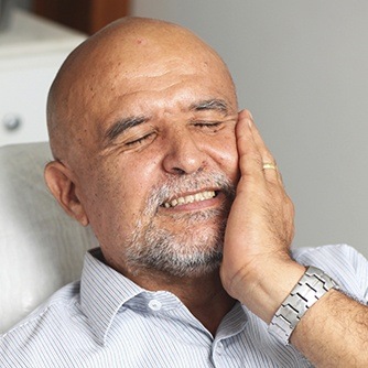 Man in dental chair holding cheek