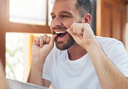 Man flossing his teeth in bathroom