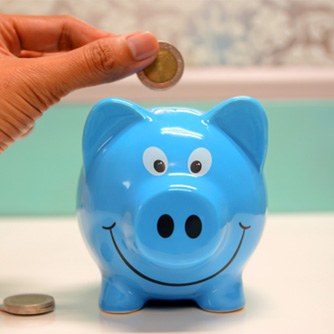 Hand putting coin in blue piggy bank