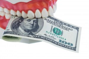 A denture holding a $100 bill.