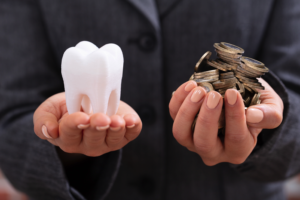 3D model of a tooth next to a handful of coins