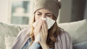 woman with seasonal allergies blowing her nose 