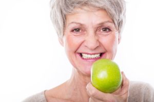 Woman using denture adhesive holding an apple