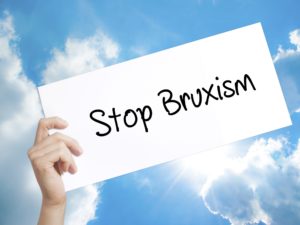 Hand holding “stop bruxism” sign