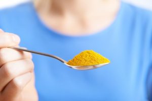 woman holding spoonful of turmeric 