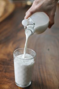 Close up of a hand pouring a glass of milk