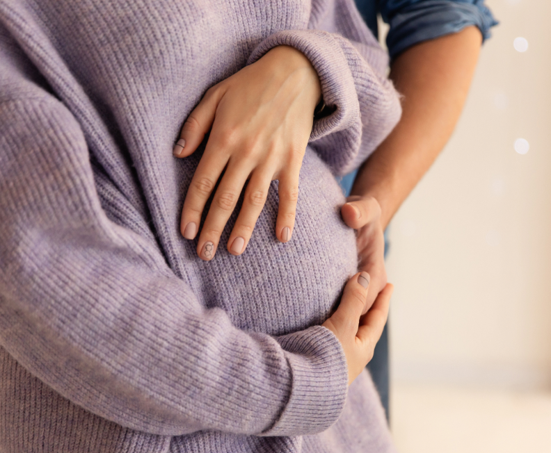Woman and partner with hands on woman's pregnant stomach